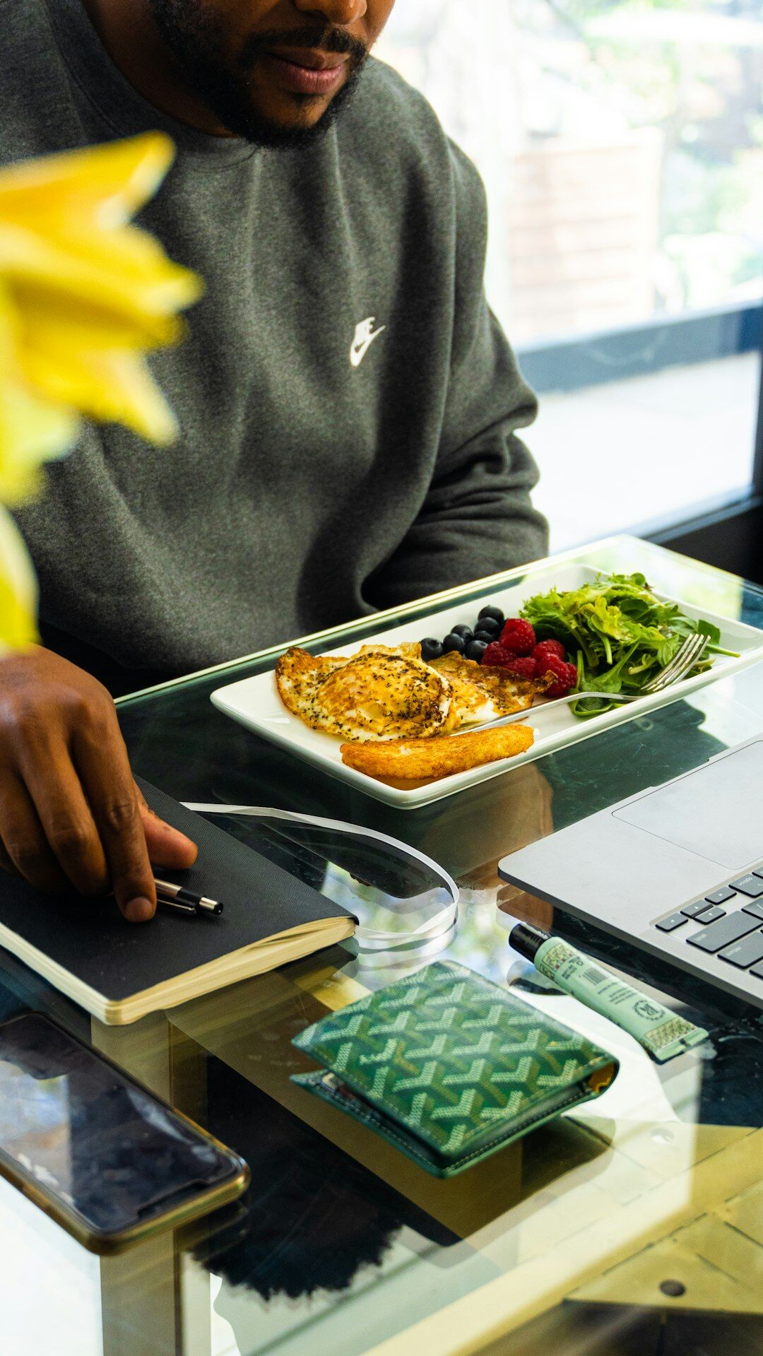 Close-up of hands writing notes next to an open laptop on a desk