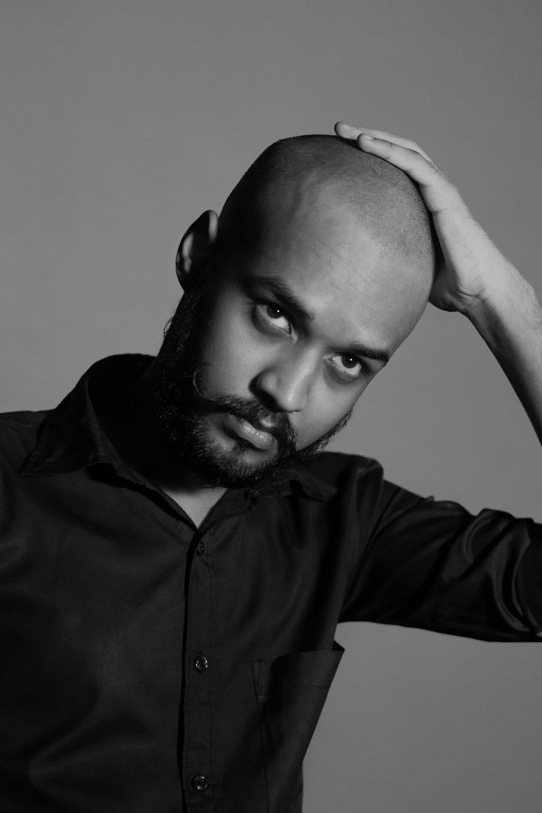 Studio portrait of a Black man with a beard wearing a shirt